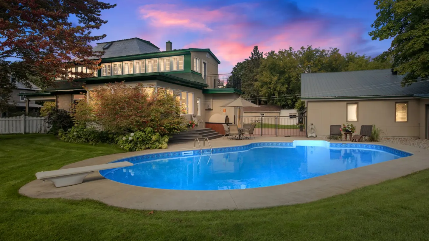 a backyard with a pool and a house in the background