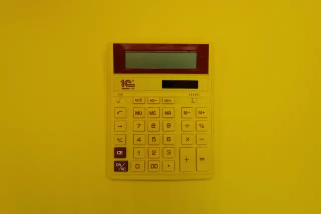a calculator mounted on a yellow wall