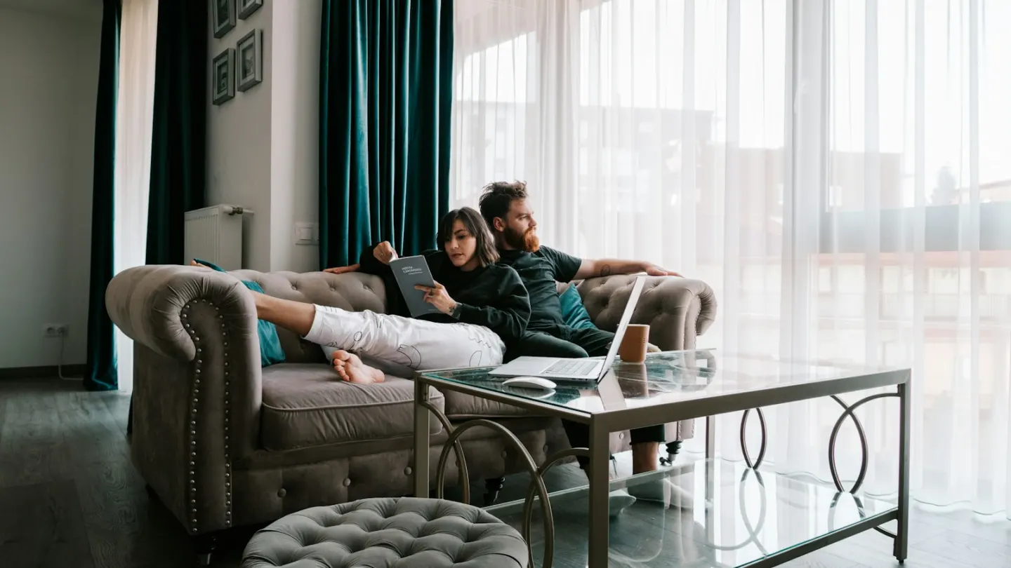 2 women sitting on sofa near window