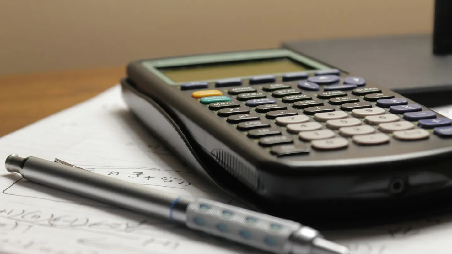 a calculator and a pen sitting on top of a piece of paper
